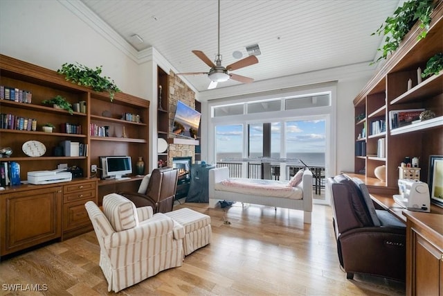 office area featuring ceiling fan, built in desk, a fireplace, ornamental molding, and light wood-type flooring