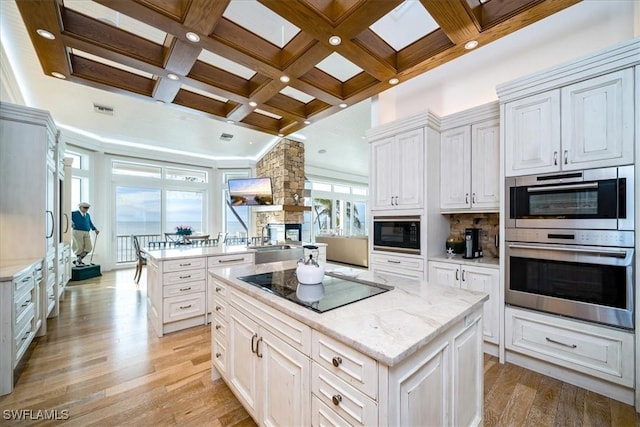 kitchen featuring white cabinetry, a center island, light hardwood / wood-style floors, and black appliances