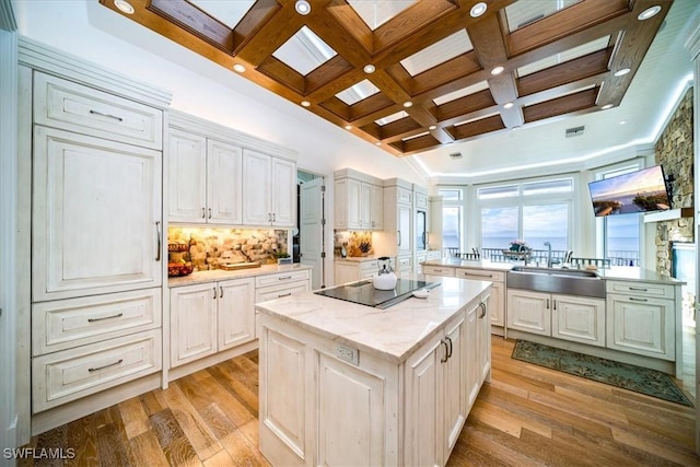 kitchen with white cabinetry, black electric stovetop, a center island, and sink