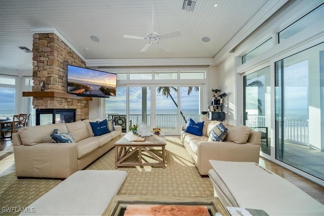 sunroom featuring a stone fireplace, lofted ceiling, and ceiling fan