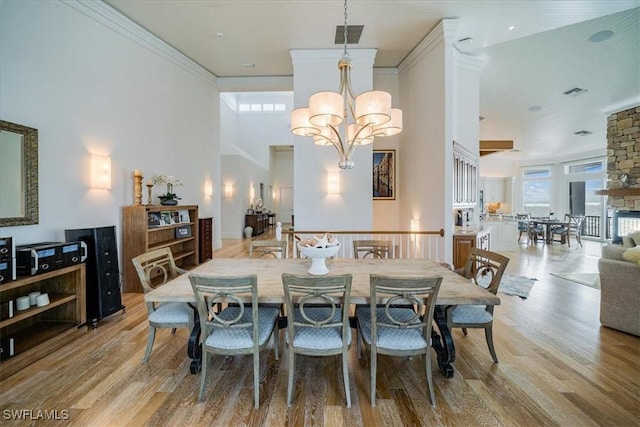 dining space with ornamental molding, a healthy amount of sunlight, a chandelier, and light hardwood / wood-style floors