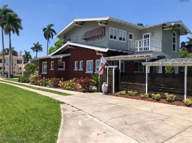 view of front of house with a balcony and a front lawn