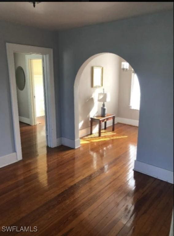 1249 Osceola Dr, Fort Myers, FL 33901 - unfurnished room with arched walkways, wood-type flooring, and baseboards
