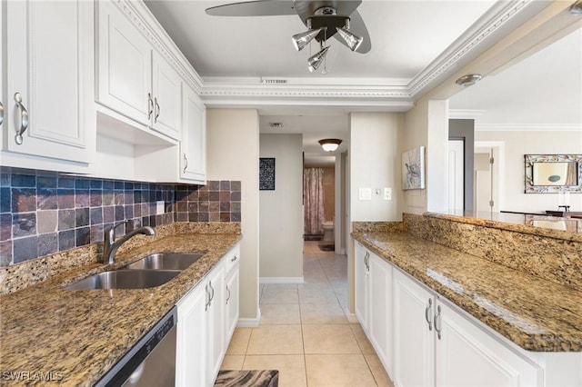 kitchen featuring dark stone counters, sink, light tile patterned floors, ornamental molding, and white cabinetry