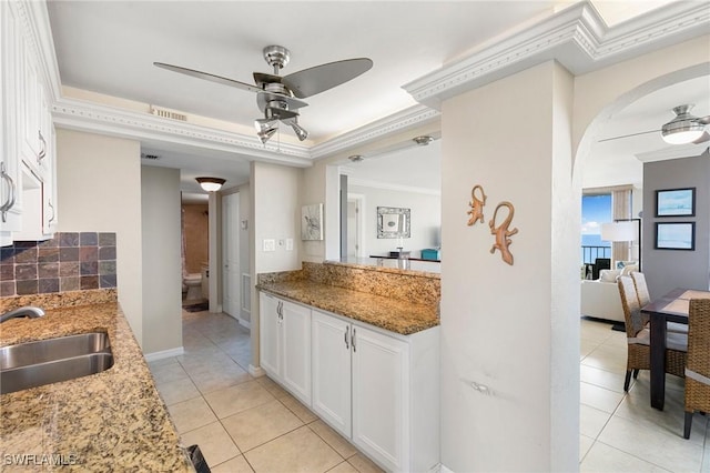 kitchen featuring white cabinets, sink, ceiling fan, ornamental molding, and stone countertops