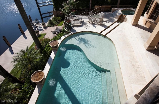 view of pool featuring an in ground hot tub, a patio, and a water view