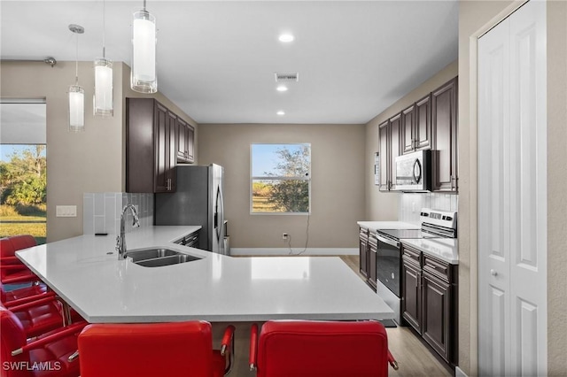 kitchen with a kitchen bar, backsplash, stainless steel appliances, and sink