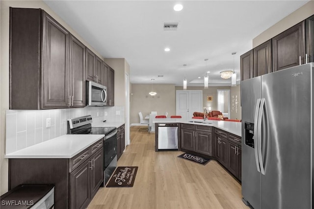 kitchen with light hardwood / wood-style flooring, kitchen peninsula, pendant lighting, decorative backsplash, and appliances with stainless steel finishes