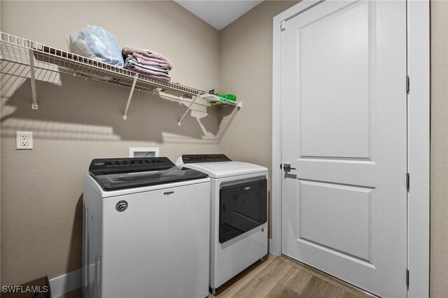 laundry area with light hardwood / wood-style flooring and washing machine and clothes dryer