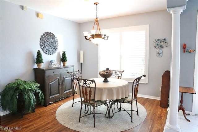 dining area with a notable chandelier, hardwood / wood-style flooring, and decorative columns