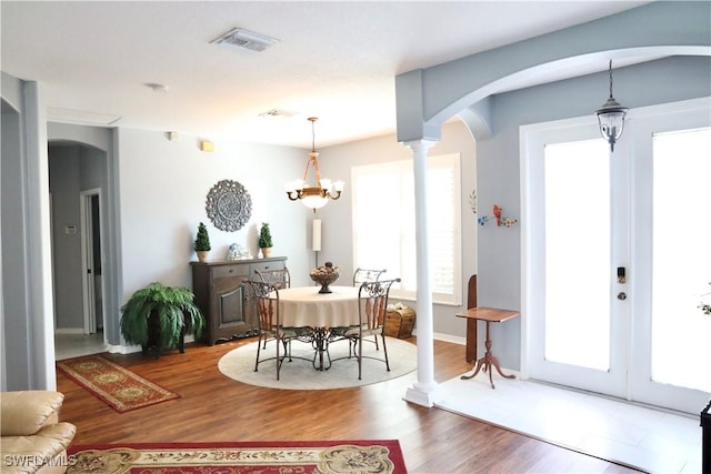 dining area with hardwood / wood-style flooring, a chandelier, and ornate columns