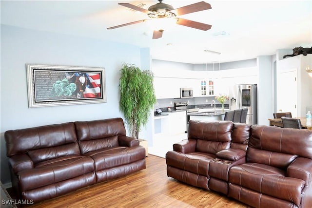 living room with sink, ceiling fan, and light hardwood / wood-style flooring