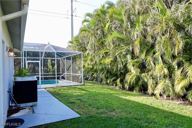 view of yard with a lanai, central AC unit, and a patio area