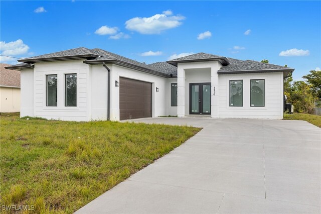 prairie-style home featuring a front lawn and a garage