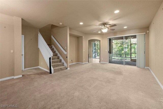 unfurnished living room with light colored carpet and ceiling fan