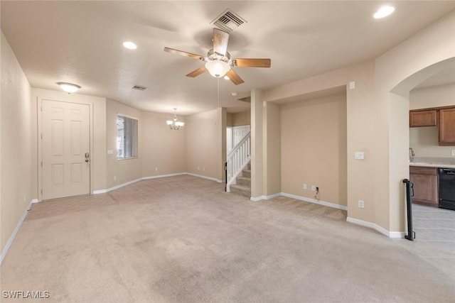 unfurnished living room featuring ceiling fan with notable chandelier and light carpet