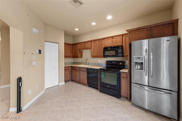 kitchen featuring sink, light tile patterned floors, and black appliances