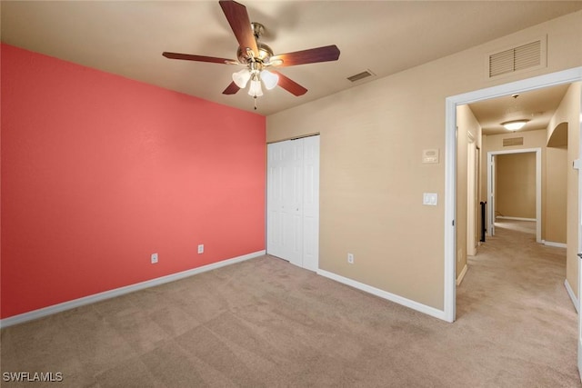 unfurnished bedroom featuring ceiling fan, light carpet, and a closet