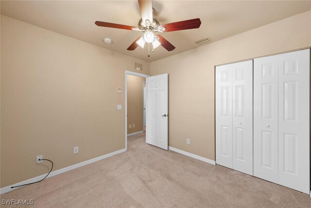 unfurnished bedroom featuring ceiling fan, a closet, and light carpet