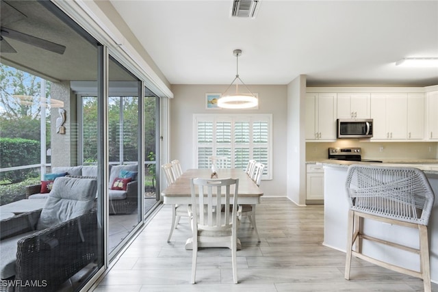 dining space with light wood-style flooring, visible vents, and ceiling fan