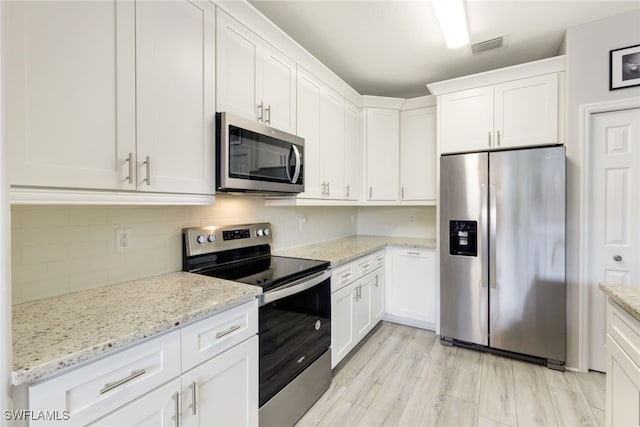 kitchen featuring white cabinetry, stainless steel appliances, and light stone counters