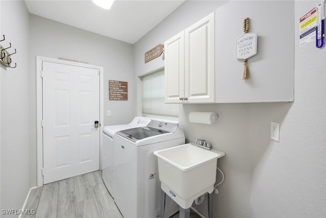 clothes washing area featuring cabinets, separate washer and dryer, light hardwood / wood-style flooring, and sink