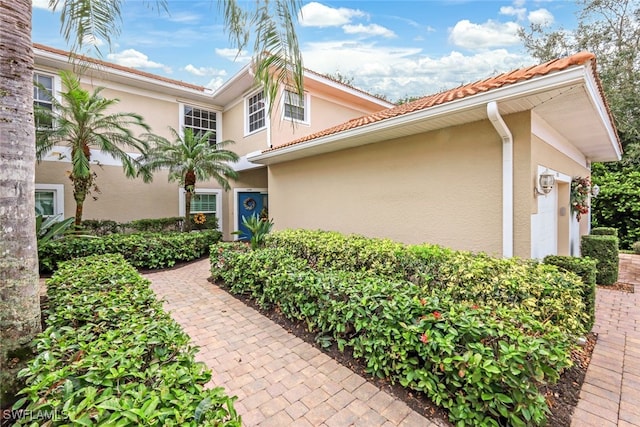 view of property exterior with stucco siding, a garage, and a tile roof