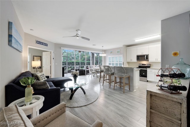 living room with ceiling fan and light hardwood / wood-style flooring