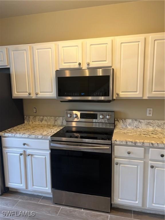 kitchen featuring light stone countertops, white cabinetry, and appliances with stainless steel finishes