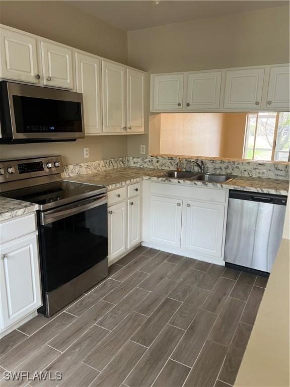 kitchen featuring appliances with stainless steel finishes, white cabinetry, and sink