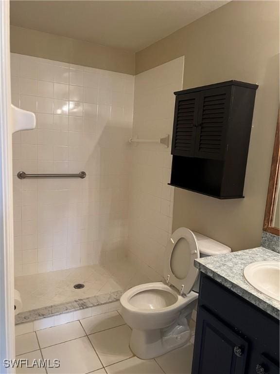 bathroom featuring tile patterned floors, vanity, a tile shower, and toilet