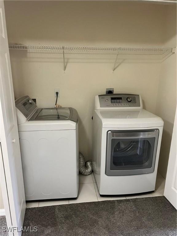 laundry area with washer and dryer and light tile patterned floors