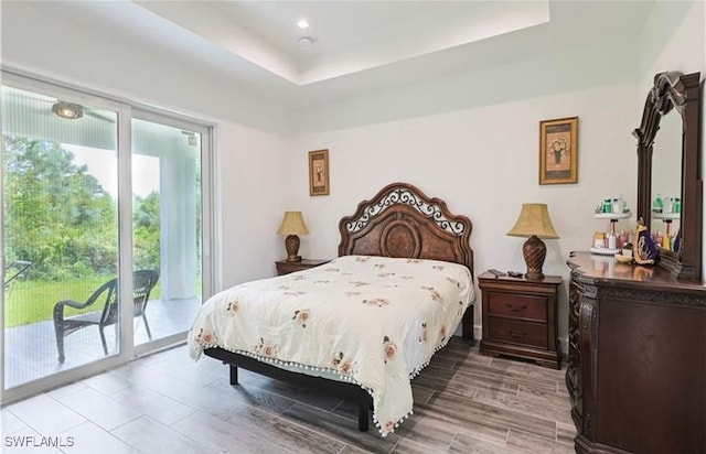 bedroom featuring access to exterior and a raised ceiling