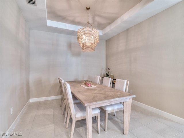 dining area with a raised ceiling, light tile patterned floors, and a chandelier