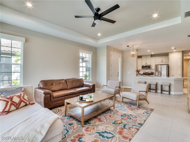 tiled living room with a tray ceiling, a wealth of natural light, and ceiling fan