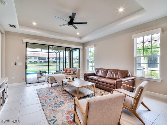 living room featuring light tile patterned floors, a tray ceiling, and ceiling fan