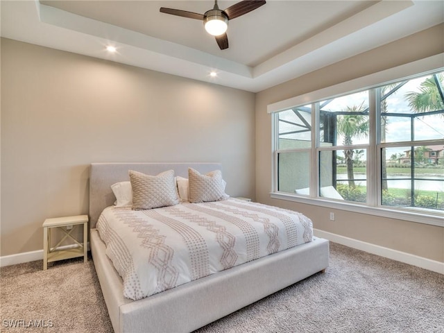 bedroom featuring light carpet, a raised ceiling, and ceiling fan