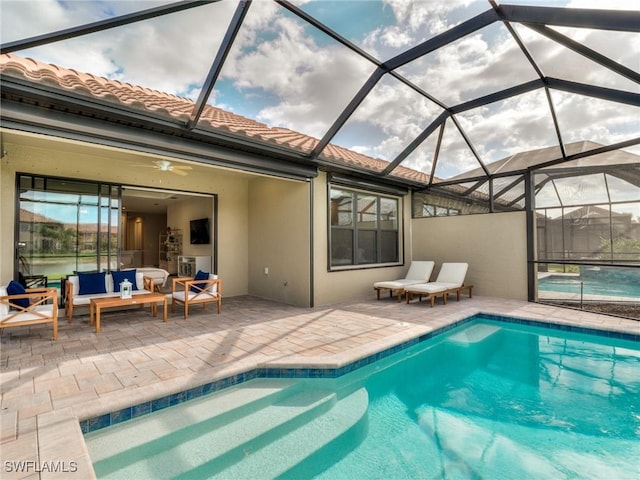 view of swimming pool with glass enclosure, ceiling fan, a patio area, and an outdoor living space