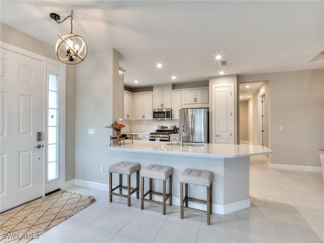 kitchen featuring appliances with stainless steel finishes, a kitchen breakfast bar, a wealth of natural light, decorative light fixtures, and white cabinets