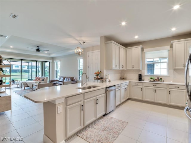 kitchen with kitchen peninsula, ceiling fan with notable chandelier, a tray ceiling, sink, and dishwasher