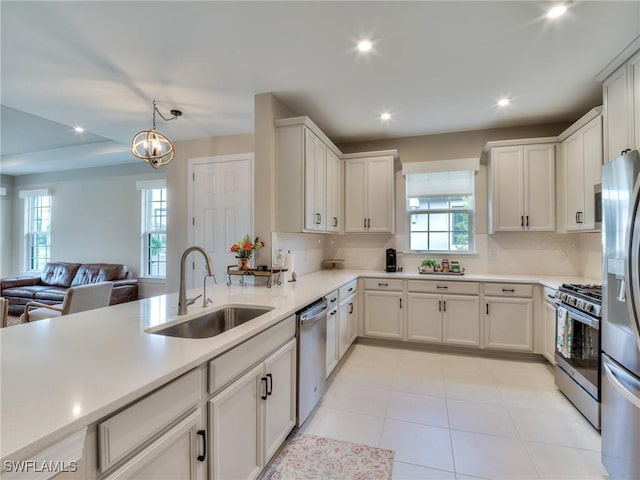 kitchen featuring decorative backsplash, appliances with stainless steel finishes, sink, decorative light fixtures, and a chandelier