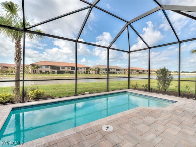 view of swimming pool with glass enclosure, a yard, a water view, and a patio