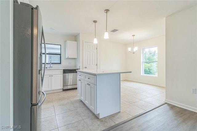 kitchen featuring a center island, decorative light fixtures, white cabinetry, stainless steel appliances, and an inviting chandelier