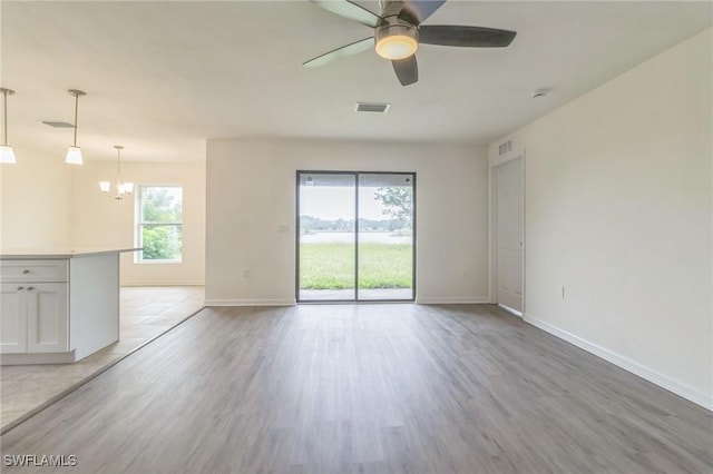 spare room featuring light hardwood / wood-style floors and ceiling fan with notable chandelier