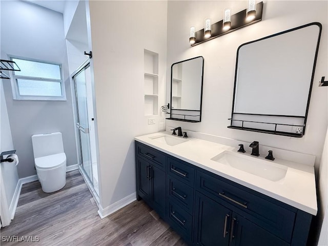 bathroom with toilet, wood-type flooring, a shower with door, and vanity