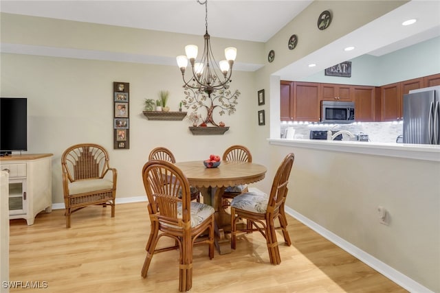 dining room with light hardwood / wood-style floors and an inviting chandelier