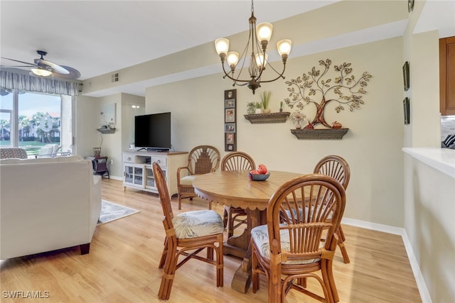 dining area with ceiling fan with notable chandelier and light hardwood / wood-style flooring