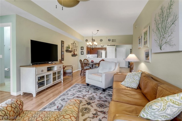 living room featuring ceiling fan with notable chandelier and light hardwood / wood-style floors