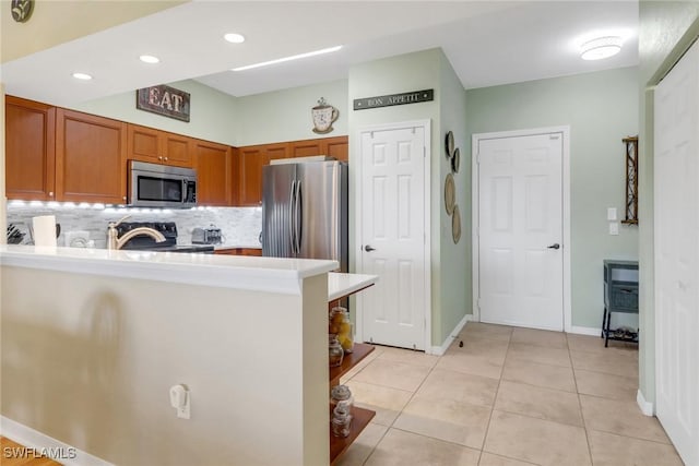 kitchen with kitchen peninsula, light tile patterned floors, backsplash, and appliances with stainless steel finishes