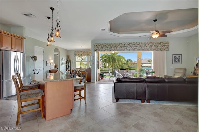 living room with ceiling fan, light tile patterned floors, and a tray ceiling